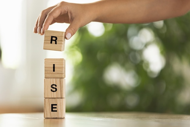 Foto la mano femenina construye una torre de bloques de cubos de madera con una imagen conceptual de word rise sobre los derechos humanos