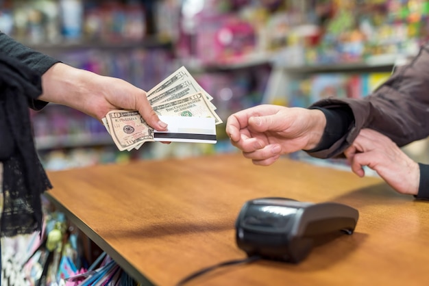 Foto mano femenina dando dólares y tarjeta al cajero como pago