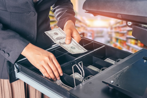 Mano femenina con dinero en tienda de supermercado.