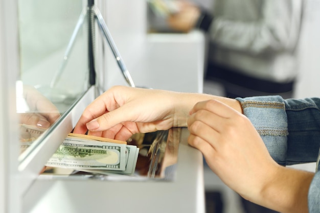 Mano femenina con dinero en la ventana del departamento de efectivo Concepto de cambio de moneda