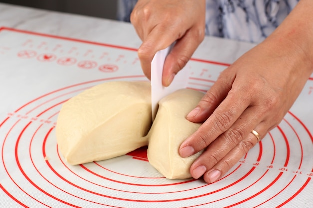 Mano femenina dividió la masa de pan o pizza en trozos más pequeños, paso a paso para hacer el pan