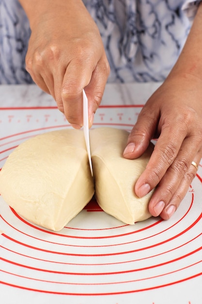 Mano femenina dividió pan o masa de pizza en trozos más pequeños paso a paso haciendo pan