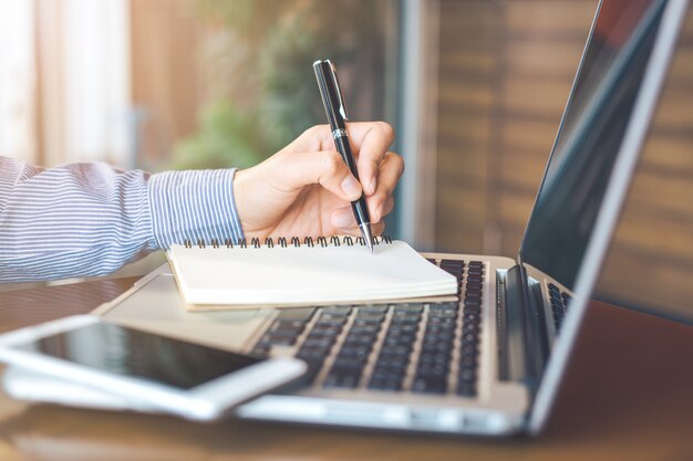 Mano femenina está escribiendo en el Bloc de notas con lápiz en la oficina