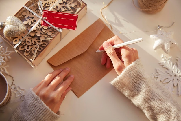 Mano femenina firma un sobre festivo Preparación para las vacaciones de Navidad