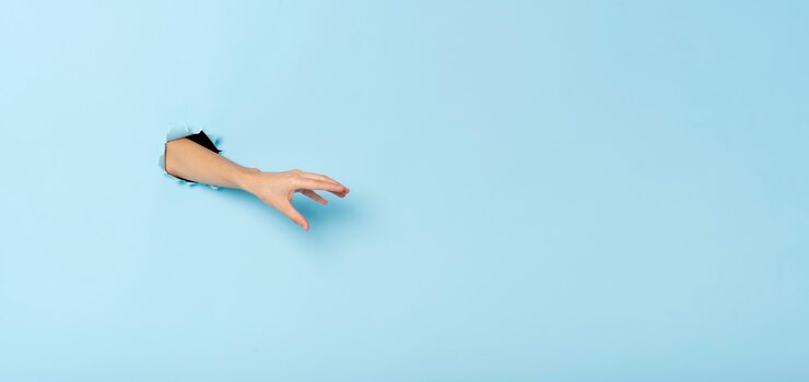 Foto mano femenina gesticulando llegar a coger algo sobre fondo azul de la bandera. imagen panorámica