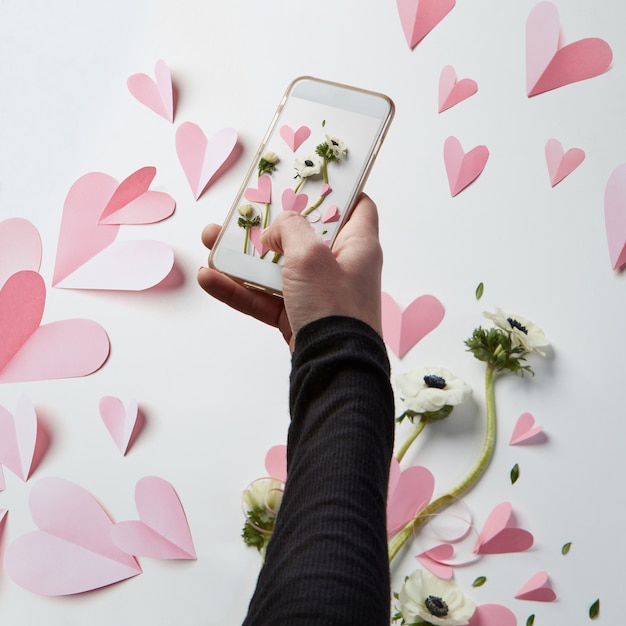 Foto mano femenina haciendo fotos de decoración en el día de san valentín. cámara del teléfono móvil haciendo imágenes de corazones.