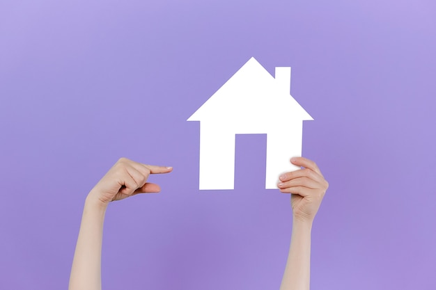 Foto mano femenina levantando y apuntando a casa pequeña