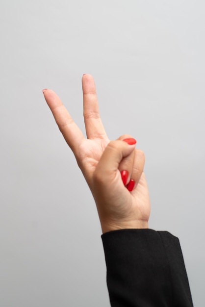 Foto mano femenina con manicura roja muestra gesto sobre fondo blanco.