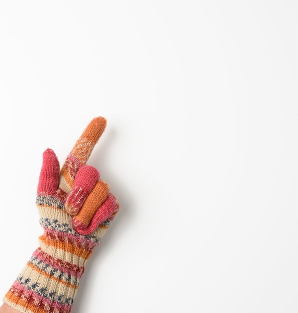 Foto mano femenina en una manopla de punto sobre un fondo blanco, el dedo índice está levantado