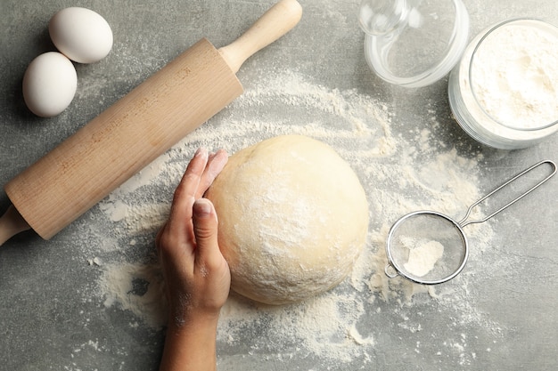 Mano femenina mantenga la masa sobre la superficie gris con ingredientes para hornear