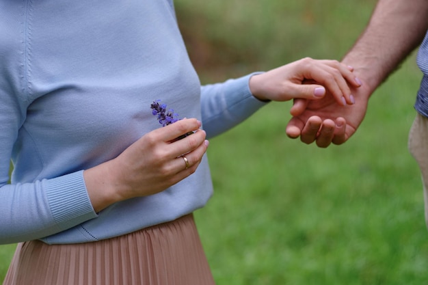 Mano femenina y masculina se mantienen juntas y flores silvestres en la naturaleza Primera cita y amor pareja romántica