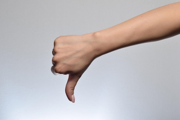 Mano femenina mostrando el pulgar hacia abajo signo en fondo blanco emociones humanas negativas signos de sentimientos