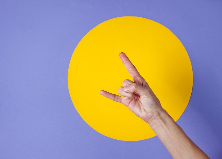 Foto mano femenina muestra gesto de rock en morado con círculo amarillo