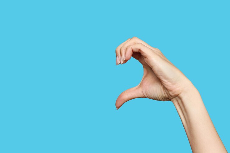 Foto la mano femenina muestra un signo en forma de medio corazón sobre un fondo azul expresión de sentimientos