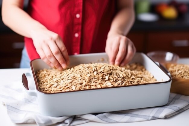 Foto mano femenina nivelando la superficie de muesli en una fuente para hornear