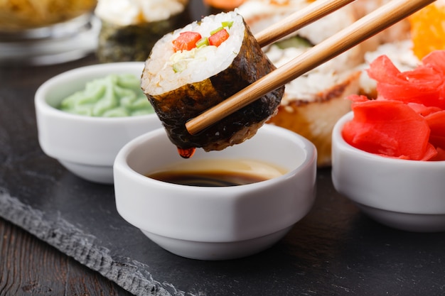 Mano femenina con palos de madera Philadelphia roll con salmón