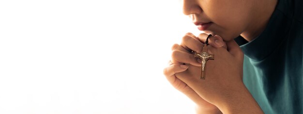 La mano femenina plegada sosteniendo la cruz mientras reza fielmente a Dios.