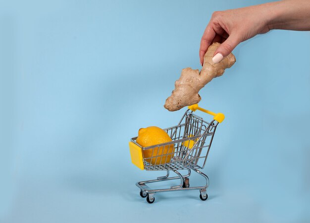 Una mano femenina pone jengibre en un carrito de supermercado