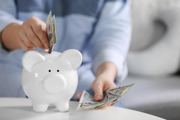 Mano femenina poniendo dinero en alcancía closeup