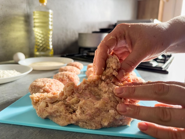 Foto la mano femenina prepara albóndigas con carne cruda en la mesa de la cocina