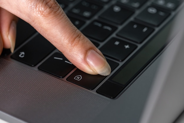 Mano femenina de primer plano presionando una tecla de retroceso para eliminar en un teclado de computadora portátil