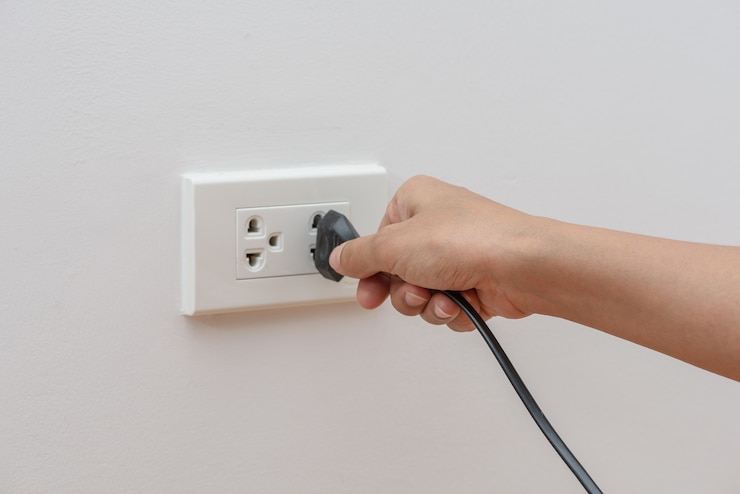 Mano femenina que intenta enchufar el dispositivo al mercado eléctrico en la pared. Concepto de ahorro de energía