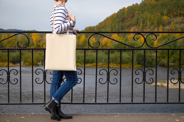 Mano femenina que sostiene la bolsa de asas ecológica de lona maqueta