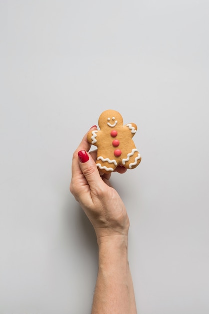 Foto mano femenina que sostiene las galletas de pan de jengibre de navidad. tarjeta de felicitación de navidad.