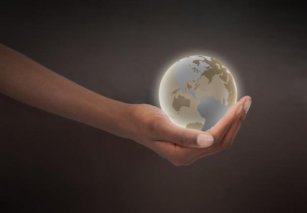 Foto mano femenina que sostiene un globo planeta resplandeciente