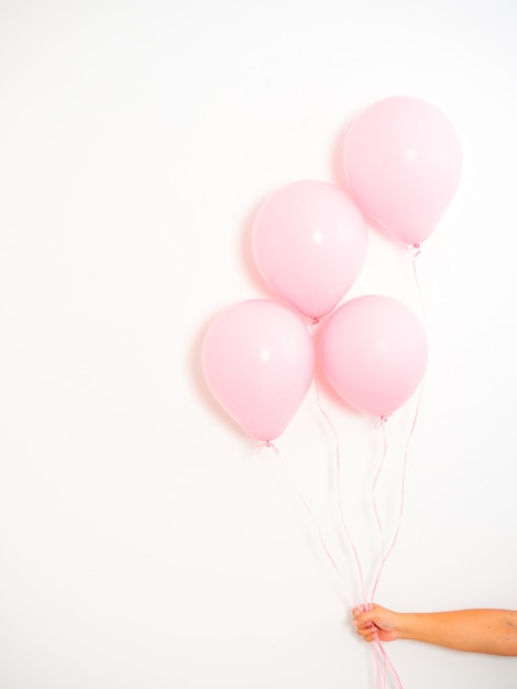 Mano femenina que sostiene los globos rosados