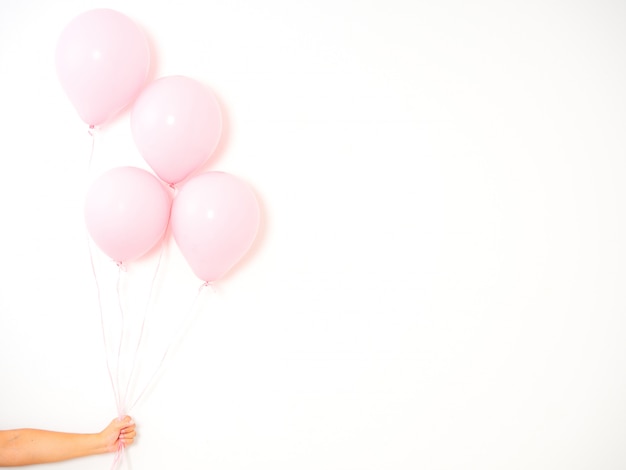 Mano femenina que sostiene los globos rosados