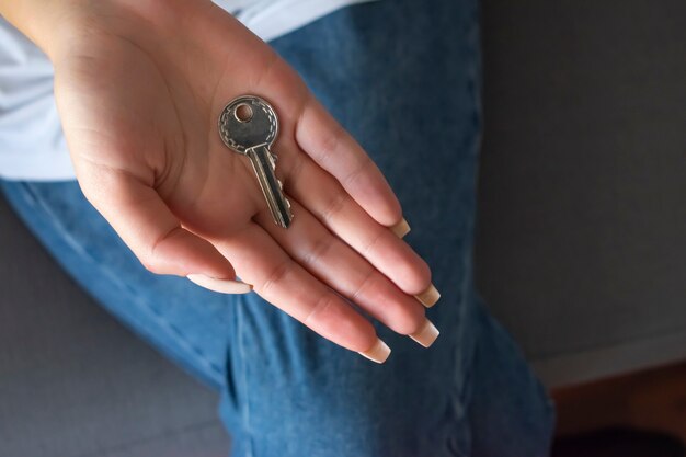 Foto mano femenina que sostiene la llave de la casa, agente inmobiliario.