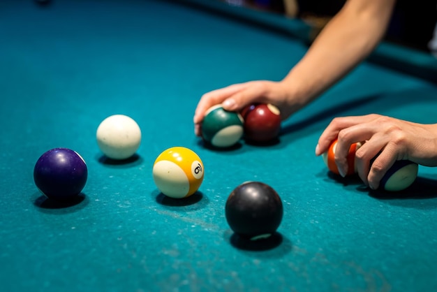 La mano femenina recoge bolas de colores después de jugar al billar y prepara un nuevo juego para pasar el tiempo libre