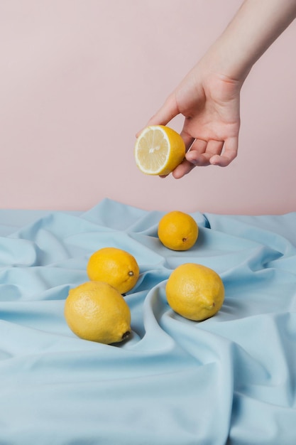 Foto mano femenina recogiendo la mitad de un limón de una mesa cubierta con cortinas azules