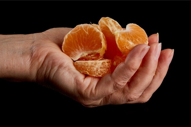 Mano femenina con rodajas peladas de jugosa mandarina madura