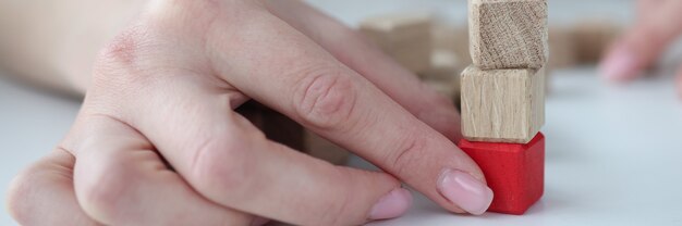 Mano femenina sacando el cubo de madera roja de la base de la torre closeup