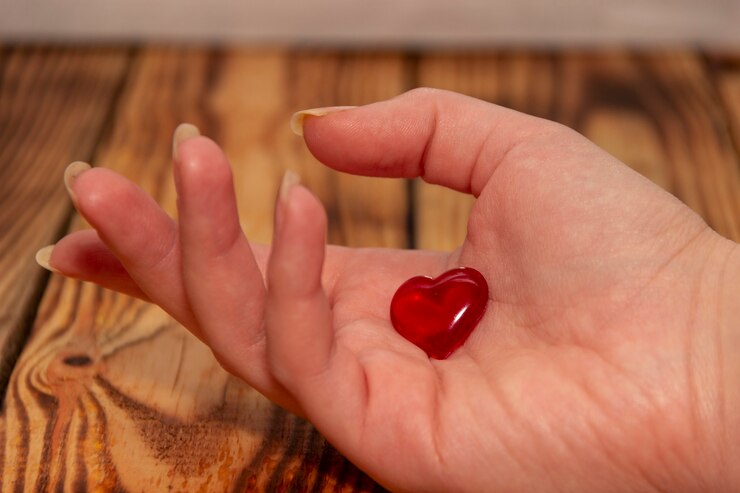 Una mano femenina sobre un fondo de madera tiene un corazón.