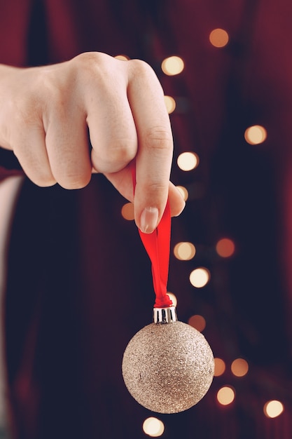 Foto mano femenina sosteniendo una bola de navidad cerrar