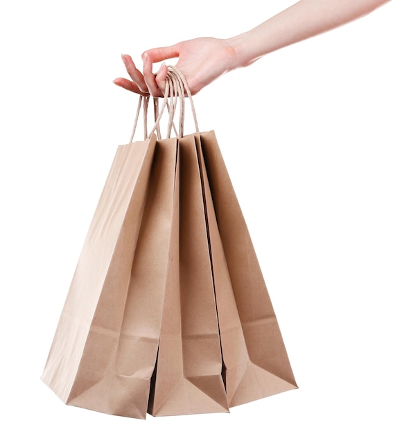 Mano femenina sosteniendo una bolsa de compras de papel aislada en blanco
