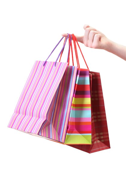 Mano femenina sosteniendo bolsas de compras brillantes aisladas en blanco