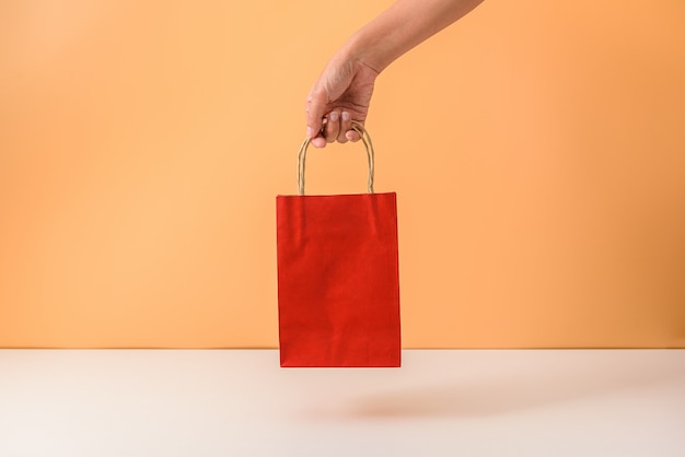 Mano femenina sosteniendo bolsas de compras papaer rojo