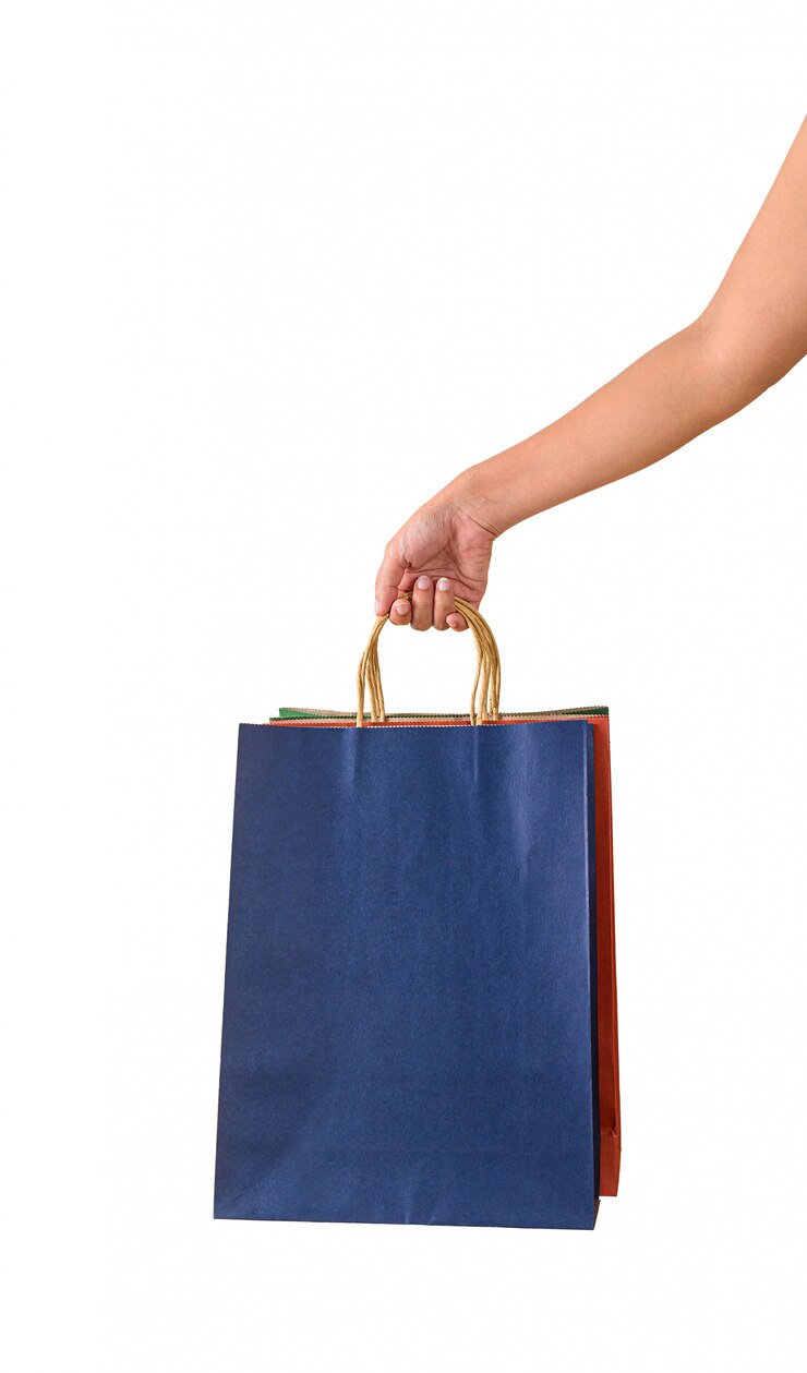 Mano femenina sosteniendo bolsas de papaer colorido en blanco