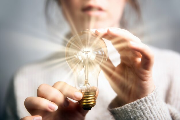 Mano femenina sosteniendo una bombilla de luz brillante gran idea innovación e inspiración concepto de negocio de nuevo ...