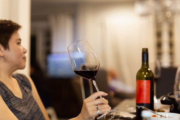 Mano femenina sosteniendo una copa de vino tinto.