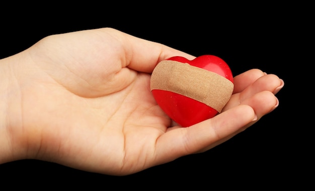 Mano femenina sosteniendo corazón con yeso en negro