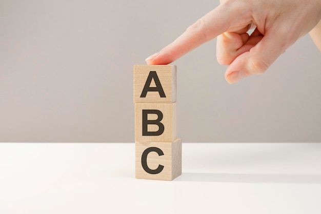 Mano femenina sosteniendo un cubo, palabras del ALFABETO en cubos de madera, concepto de regreso a la escuela, aprendiendo los conceptos básicos de la lectura.