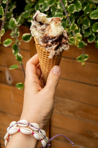 Mano femenina sosteniendo delicioso helado de chocolate con vainilla americana Sabroso helado casero Gelato en el cono de waffle Sin gluten vegano sin lácteos