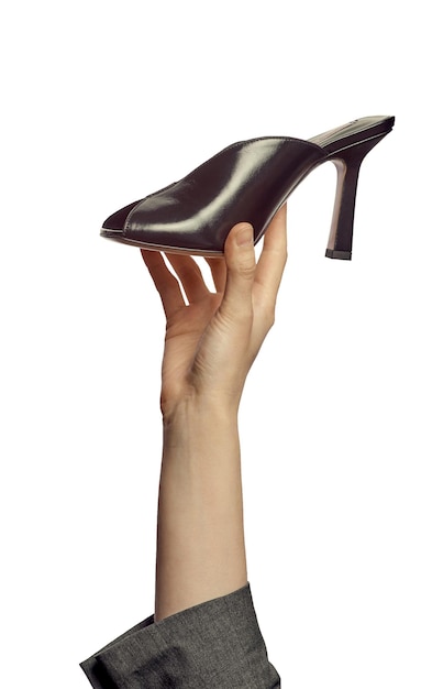 Una mano femenina sosteniendo un elegante zapato de verano de tacón alto negro abierto aislado sobre un fondo blanco Calzado de moda en la mano