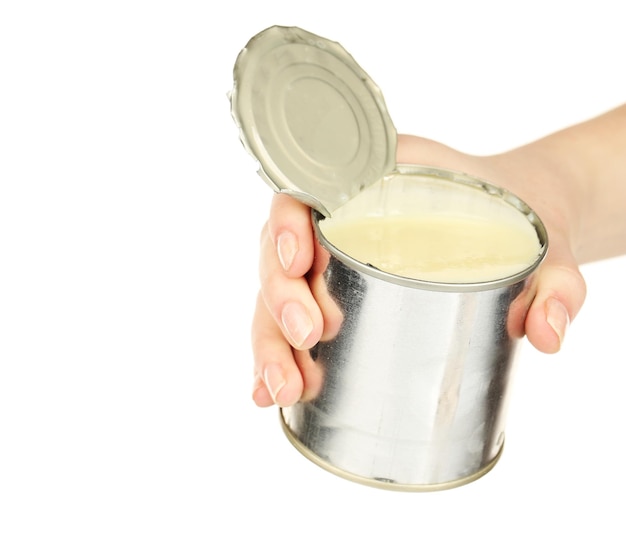 Mano femenina sosteniendo una lata de leche condensada aislada en blanco