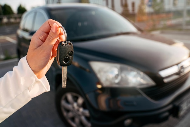 Mano femenina sosteniendo las llaves del auto, enfoque selectivo. Mujer comprando auto nuevo en el salón del automóvil